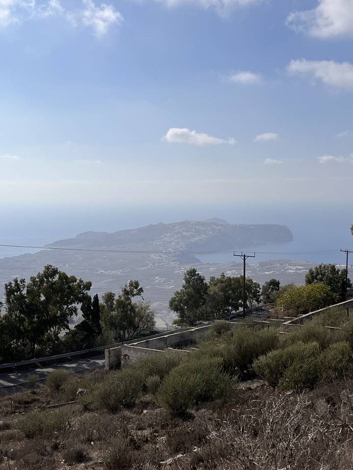 Distant view of an island with the sea and vegetation in the foreground.
