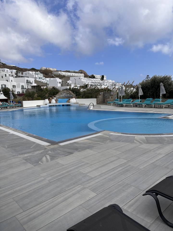 Hotel pool area with sun loungers overlooking buildings.
