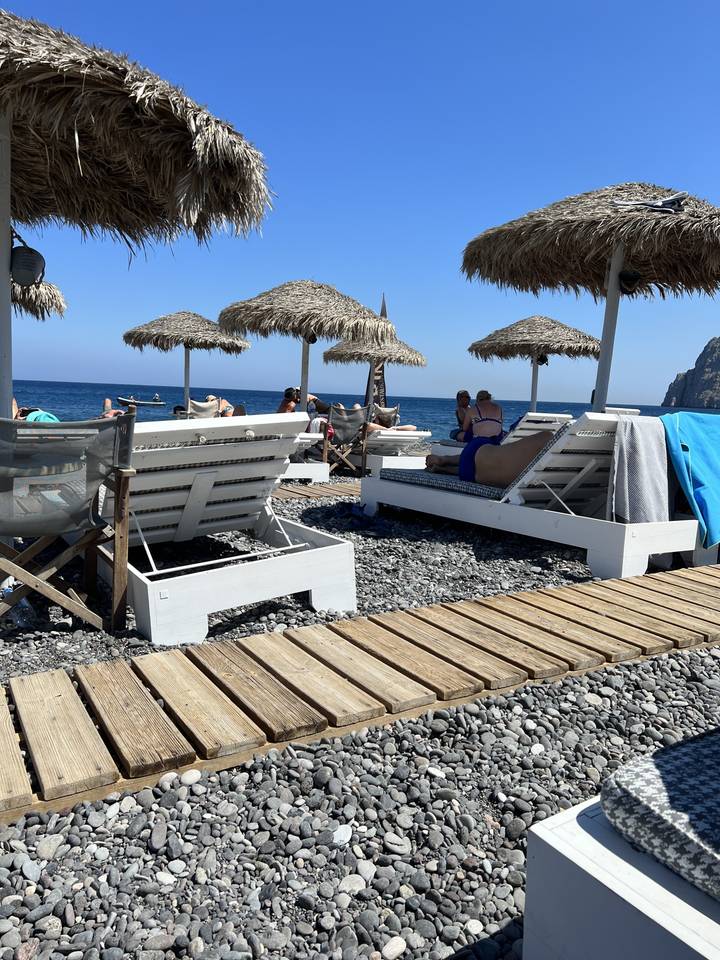 Beachside scene with people on sunbeds under umbrellas.