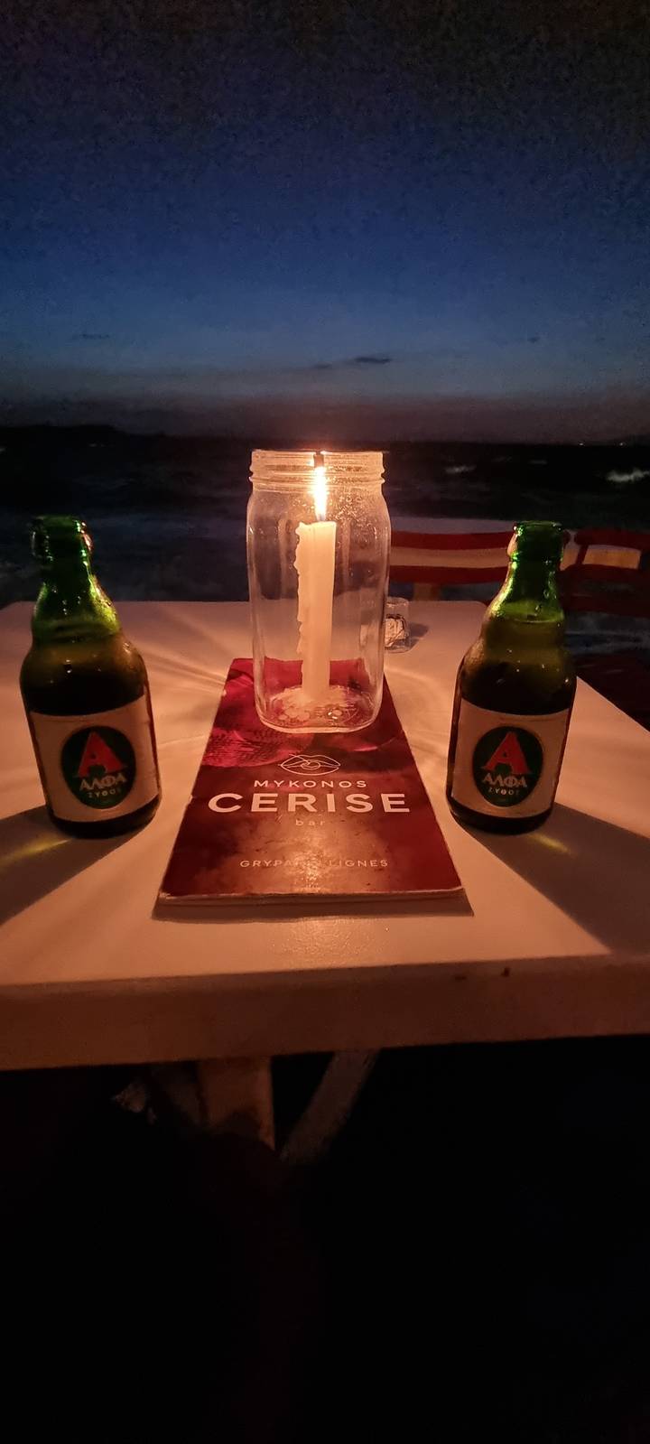 Table with a candle and bottles of beer.