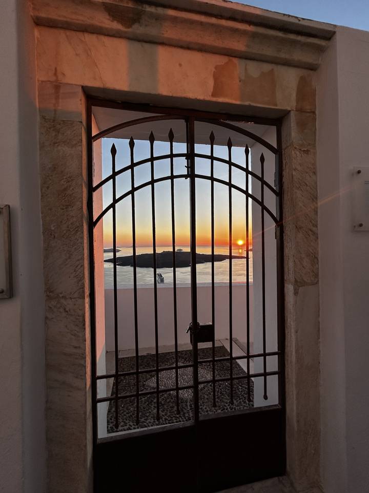 Sunset view through an iron gate overlooking the sea.