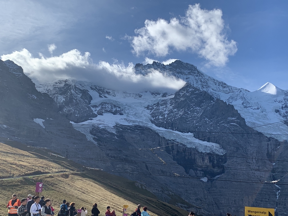 Montagnes enneigées avec des nuages et un ciel bleu.