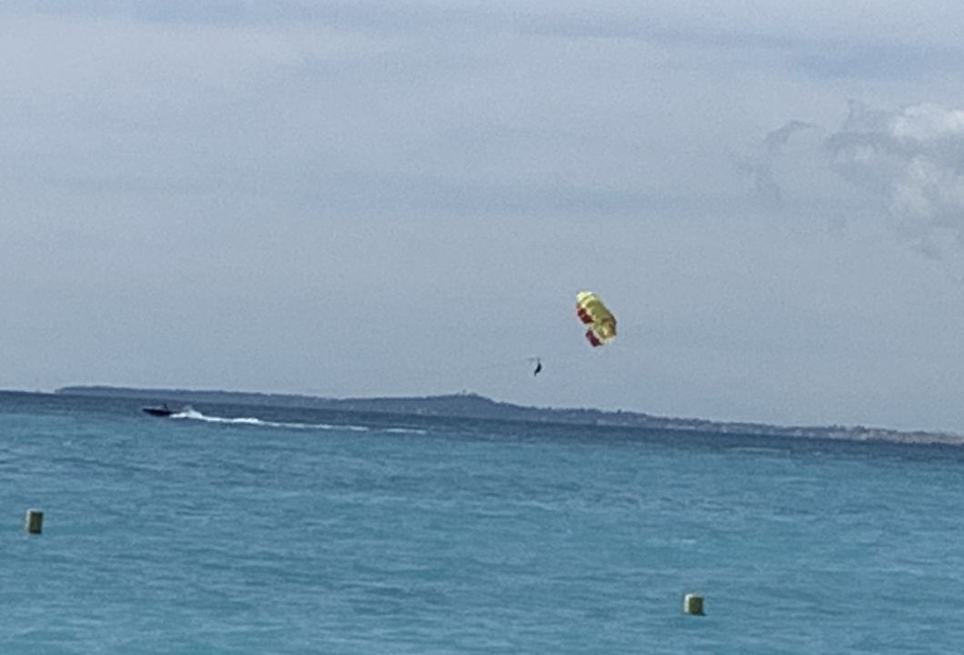 Parachute ascensionnel au-dessus d'une mer bleue avec un ciel nuageux.