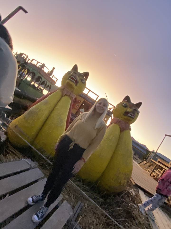 A woman posing next to large decorative statues at dusk.