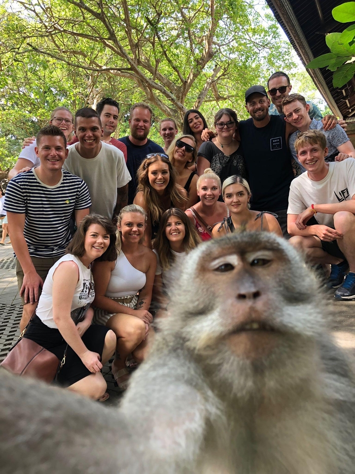 Group photo with a monkey photobombing.