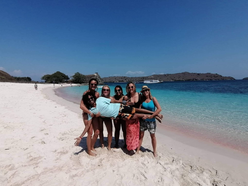Des amis qui posent sur une plage avec la mer bleue en arrière-plan.