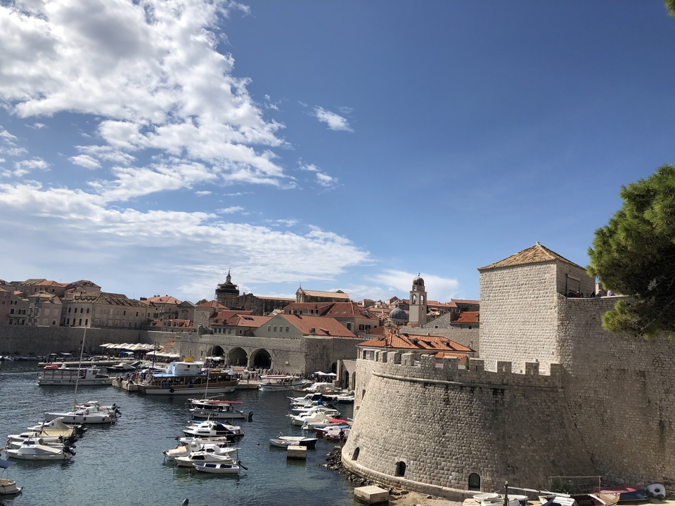 Ville côtière historique avec des bateaux et des murs de pierre.