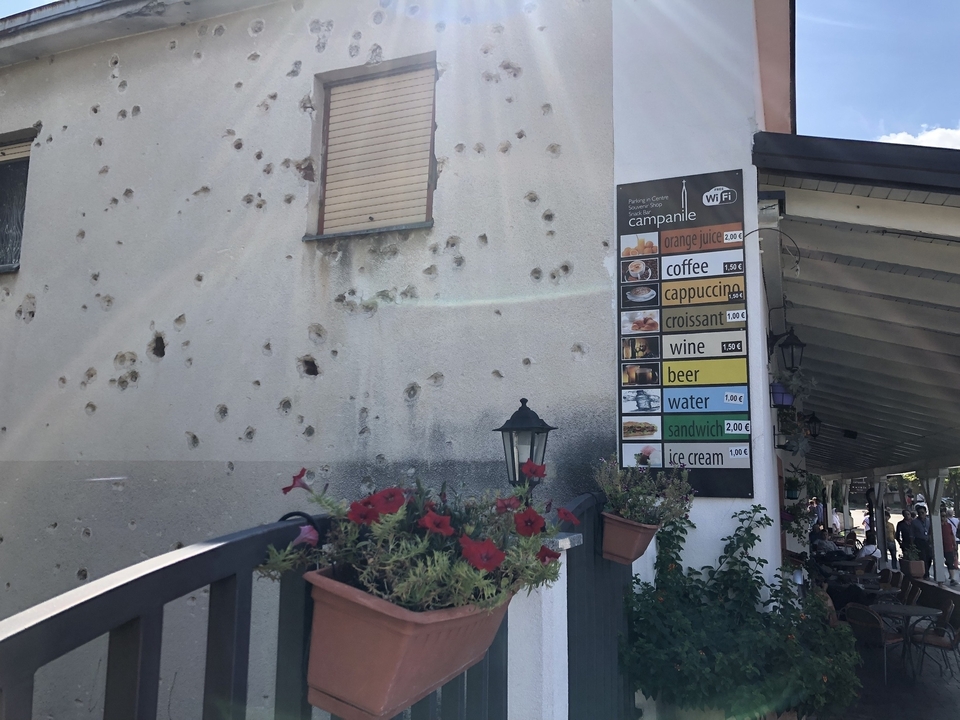 Façade de bâtiment avec des impacts de balles et un menu d'enseigne.