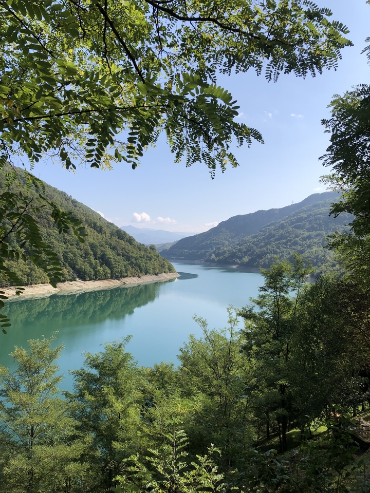Lac serein entouré de montagnes luxuriantes sous un ciel bleu.
