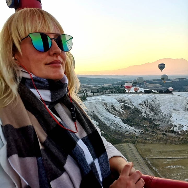 A person enjoying a view of hot air balloons over Pamukkale landscapes at sunrise.