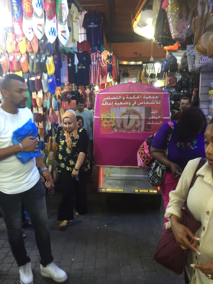 A marketplace with various goods on display and people walking by.