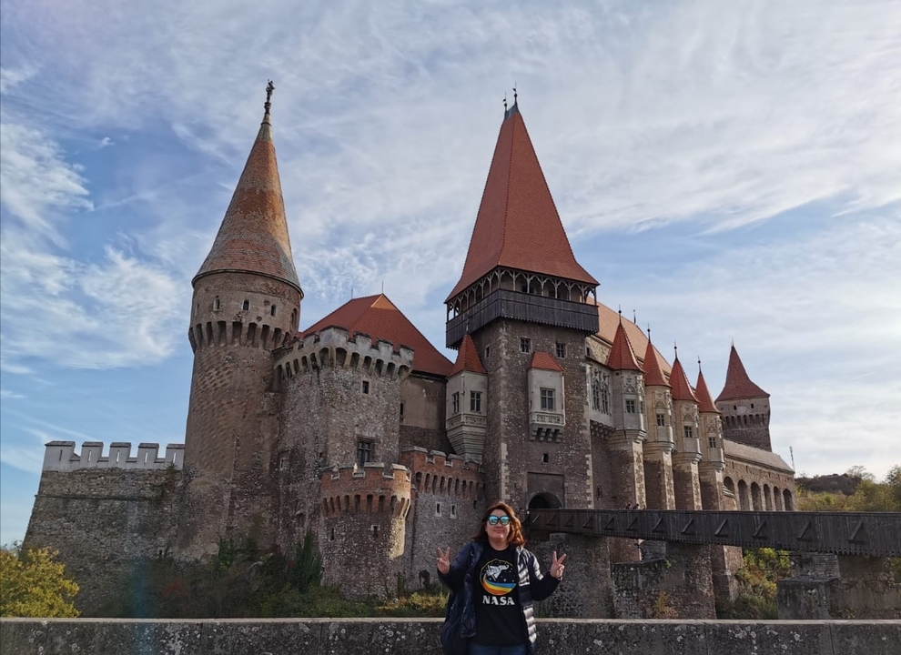A person standing in front of a large castle with multiple towers.