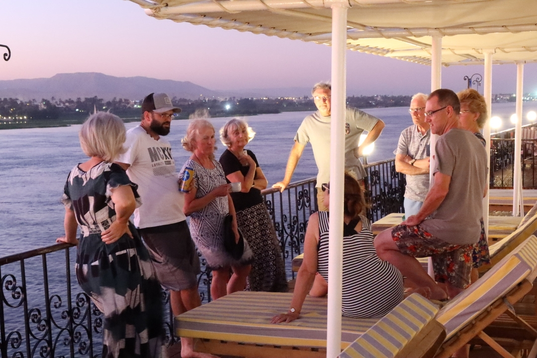 Groupe de personnes profitant du coucher de soleil sur le pont d'un bateau de croisière.