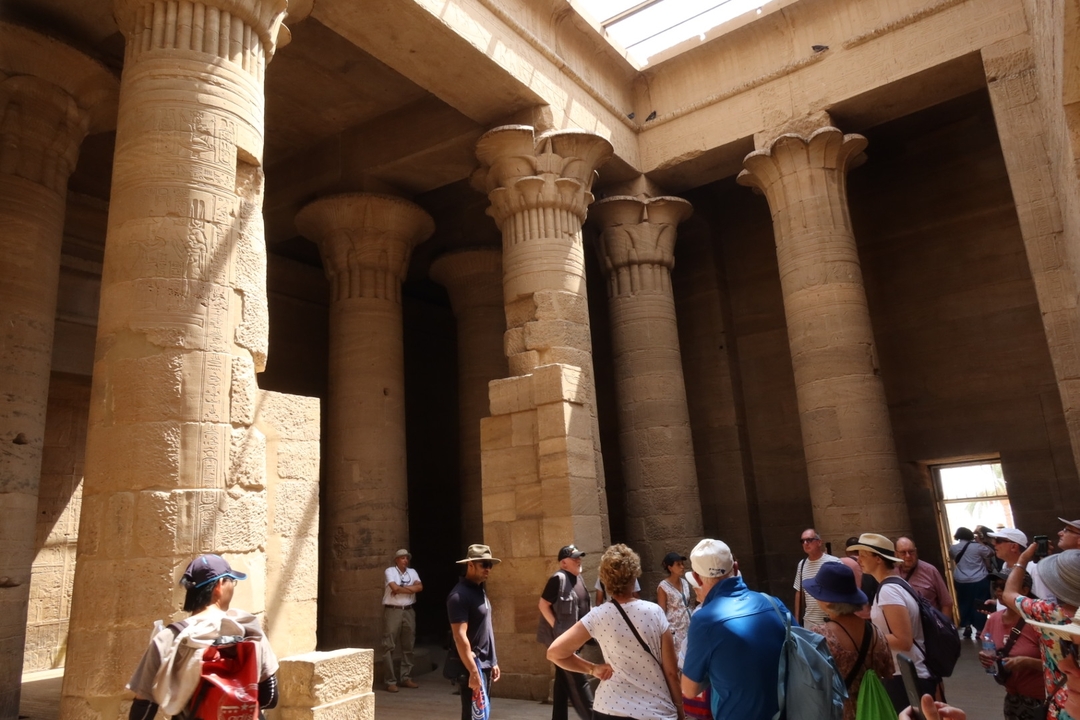 Groupe de touristes à l'intérieur d'un temple antique avec des colonnes massives.