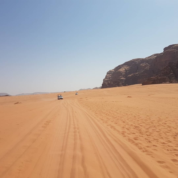 Desert landscape with vehicles in the distance.