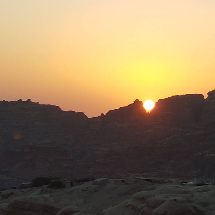 Sunset behind rocky landscape.