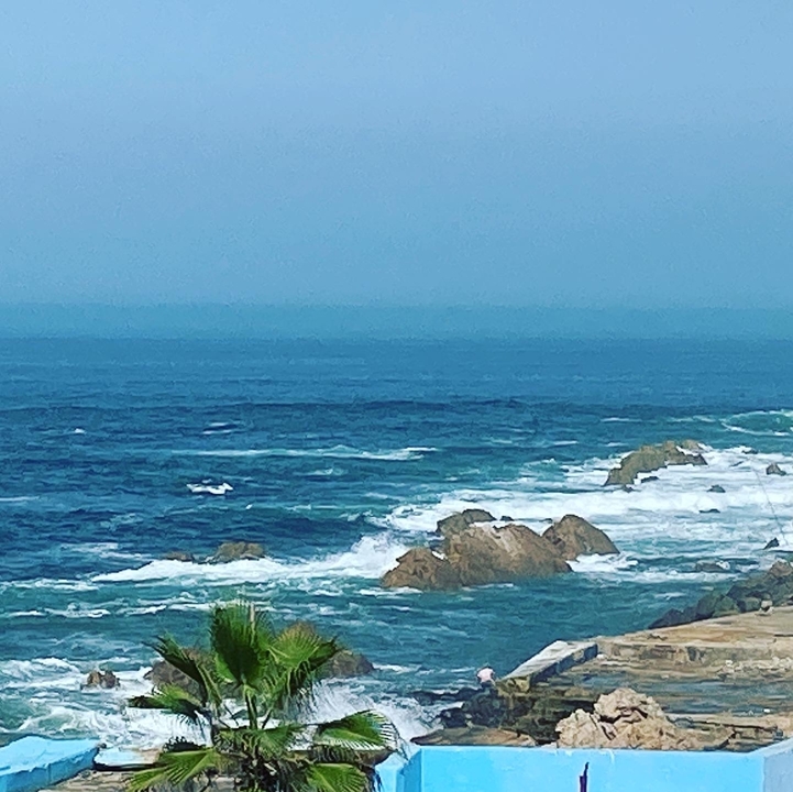 Ocean view with rocks and waves under a clear sky.