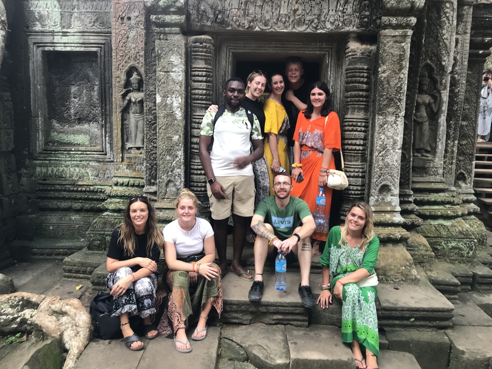 Group of people posing in front of ancient ruins.