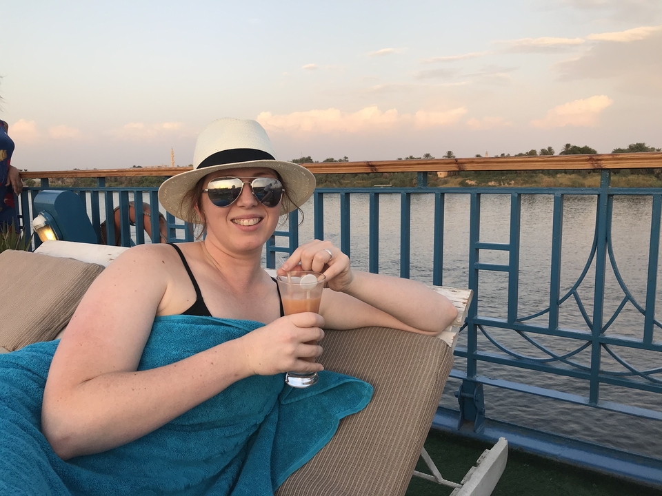 Woman relaxing with a drink on a riverboat deck.