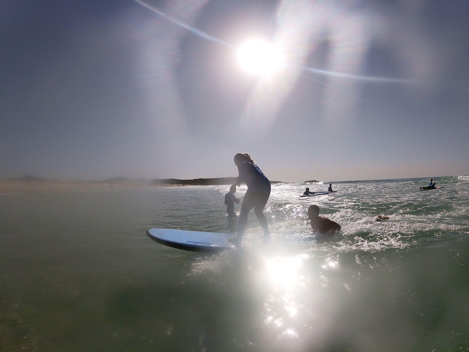 Personne faisant du surf avec le soleil au-dessus.