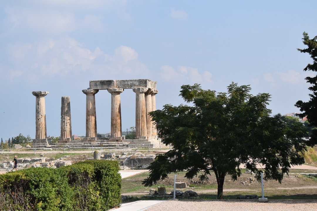 A view of Corinthian ancient ruins with columns and surrounding greenery