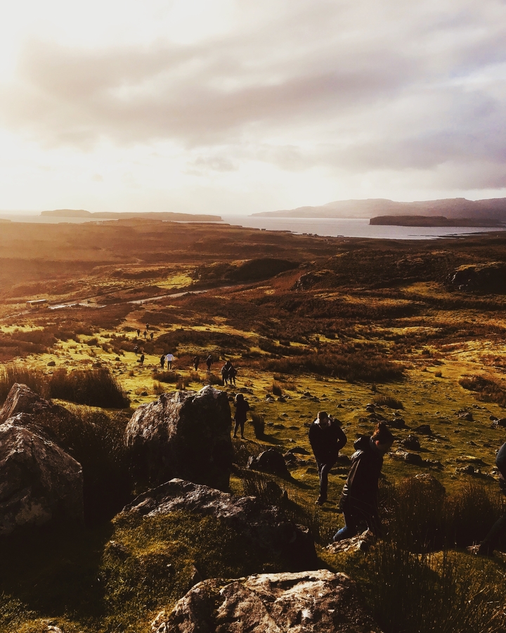 Landscape with people hiking towards a lake and hills.