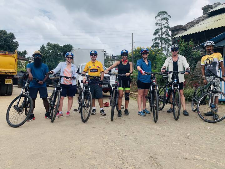 A group of people with bicycles posing together on a road.