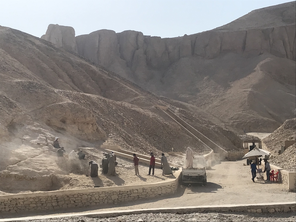Des personnes travaillant sur un site de fouilles archéologiques dans un désert rocheux.