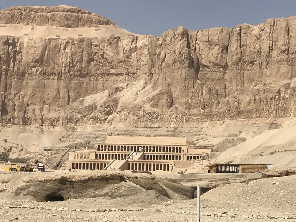 Le temple d'Hatchepsout avec une paroi rocheuse et un ciel bleu dégagé en arrière-plan.