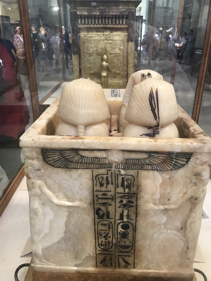 Ancien vase canope avec des sculptures détaillées dans une vitrine d'exposition.