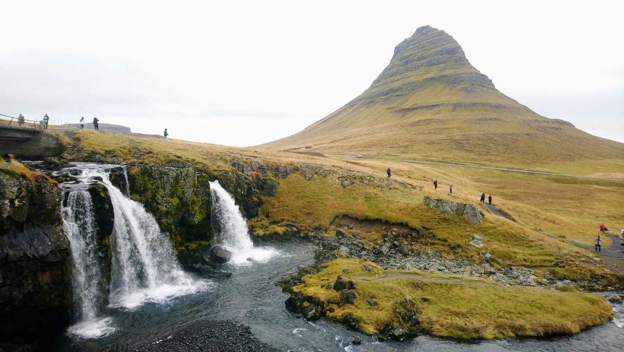 Mountain waterfall with a distinct peak in the background.
