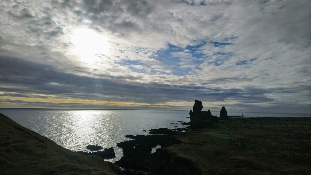 Rocky coastal landscape with the sun reflecting on the water.