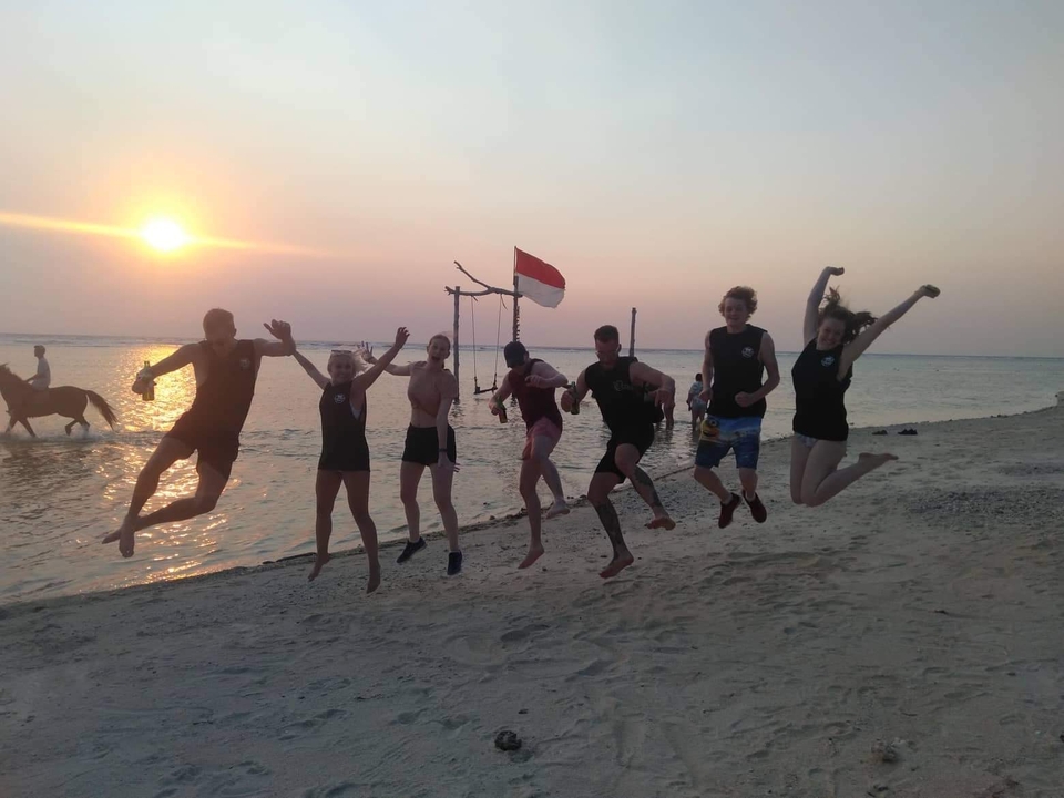 Group of friends jumping on a beach during a sunset.