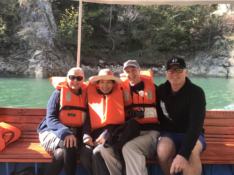 Groupe de personnes portant des gilets de sauvetage sur un bateau avec un lac en arrière-plan.