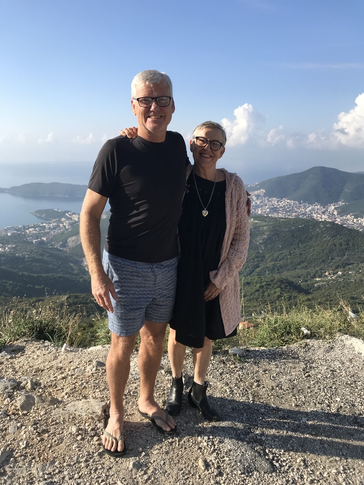 Couple posant avec une vue panoramique d'une ville et d'un littoral en arrière-plan.