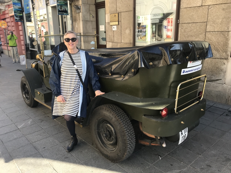 Femme posant à côté d'une voiture vintage dans la rue.
