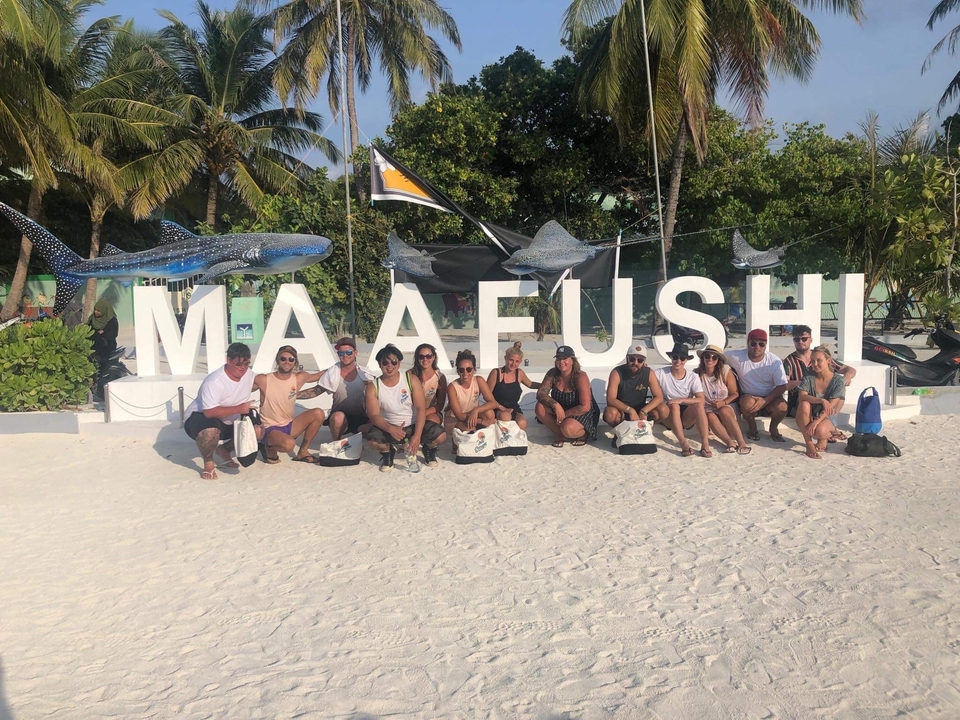 Groupe de personnes assises devant un panneau qui indique « Maafushi ».