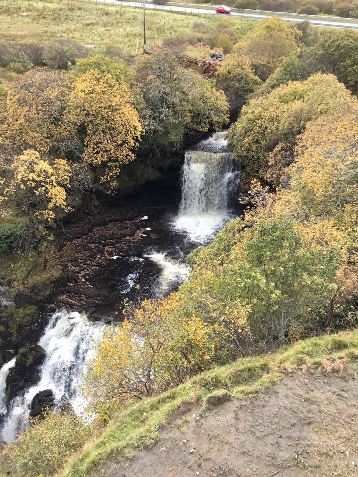 A waterfall surrounded by autumn foliage viewed from above.
