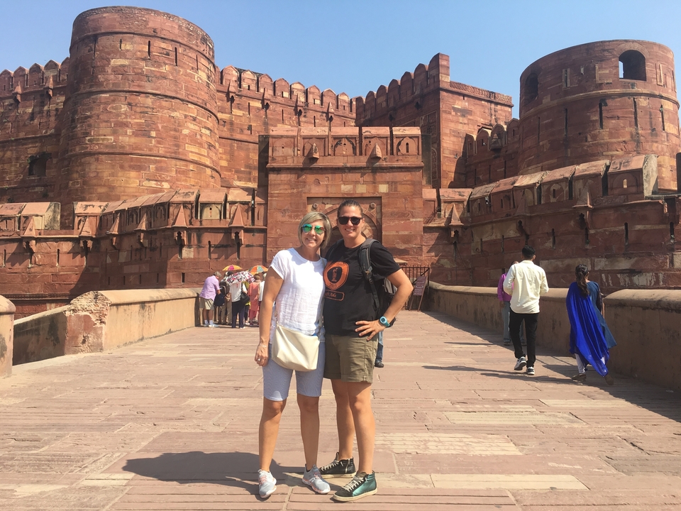 Two people posing at the entrance of a large fort.
