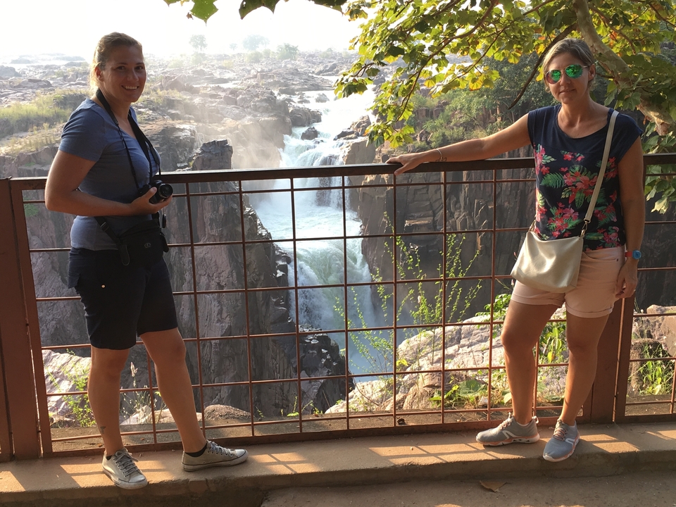 Tourists at a waterfall, enjoying the scenic view.
