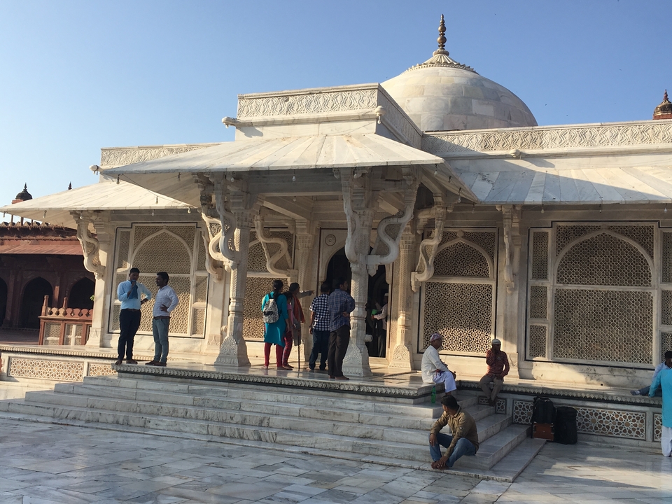 People visiting the Tomb of Salim Chishti at Fatehpur Sikri, featuring ornate architecture.