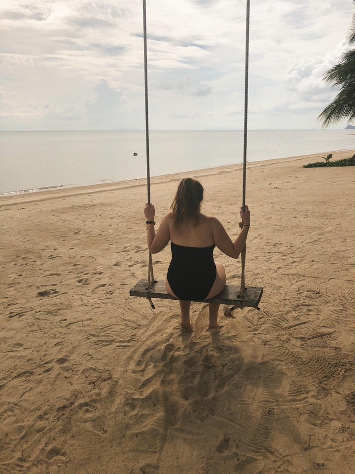 Person sitting on a swing looking at the ocean.