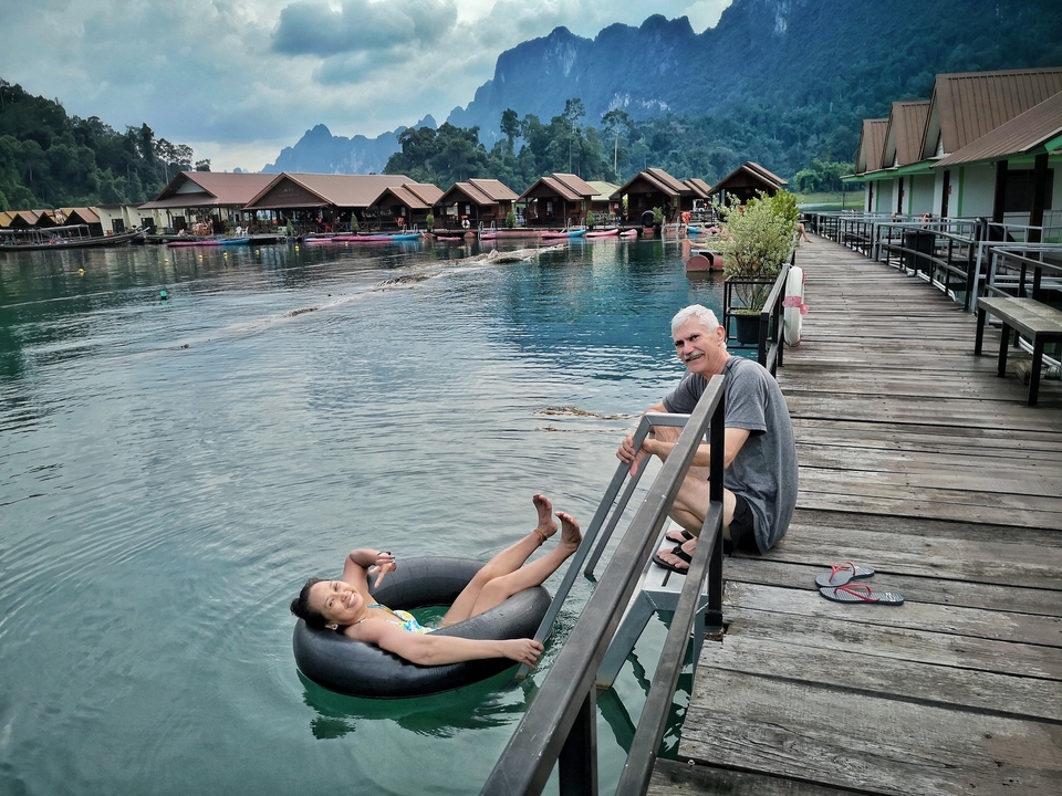 Person floating in a lake in front of floating houses.