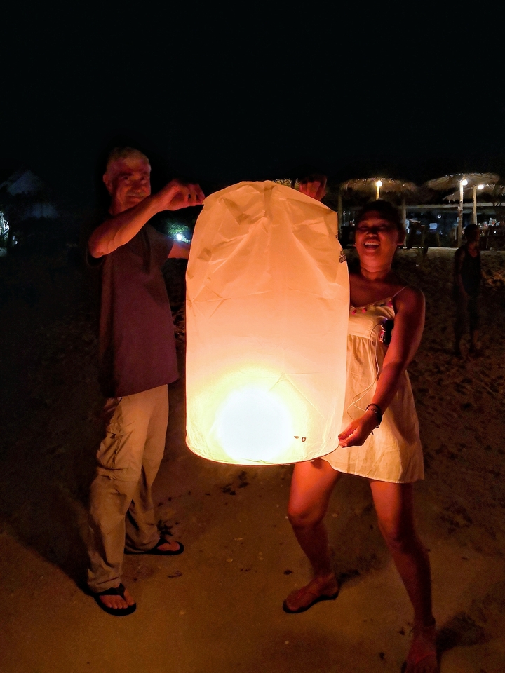 People releasing a paper lantern at night.