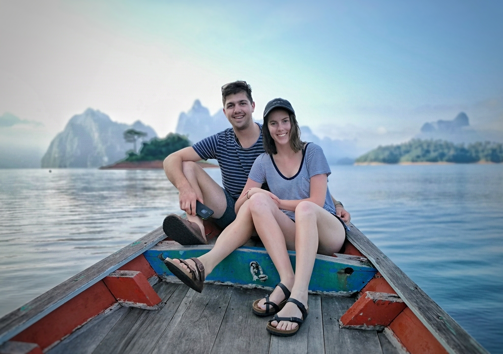 Couple sitting at the front of a boat with stunning rock formations in the background.