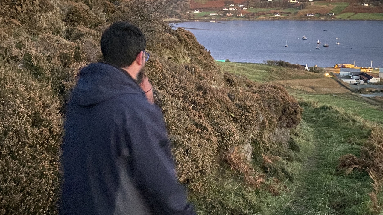 Personne regardant un village côtier depuis une colline.