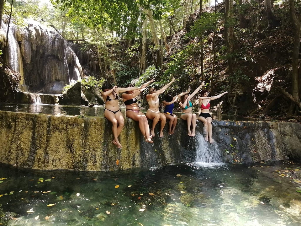 Des gens assis au bord d'un bassin naturel avec des cascades.