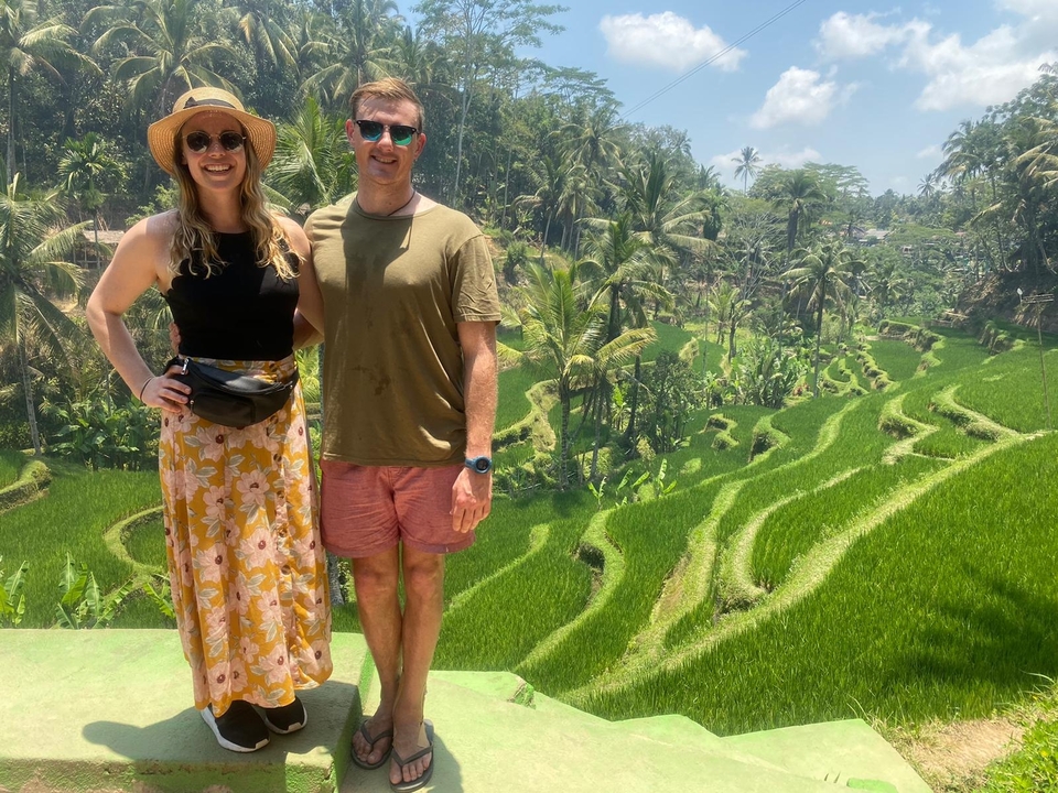 Couple posing in front of lush green rice terraces.