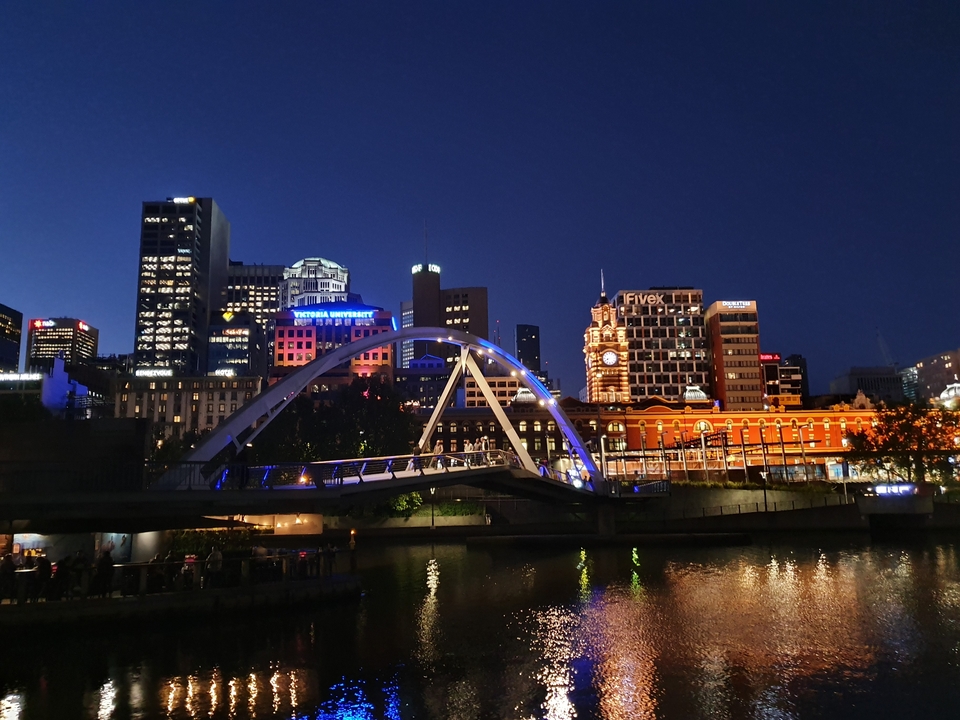 Paysage urbain de nuit avec bâtiments illuminés et pont.
