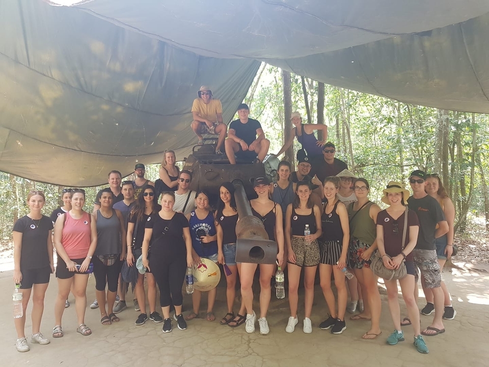 Group of people posing with a tank under a canopy.